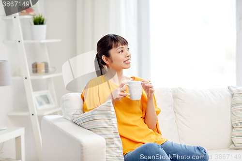 Image of happy asian woman drinking from tea cup