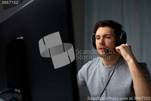 Image of man in headset playing computer video game at home