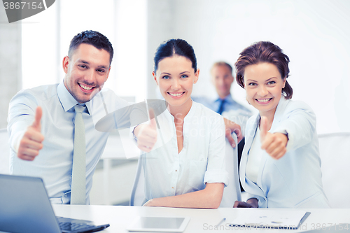 Image of business team showing thumbs up in office