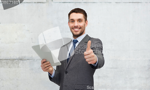 Image of young businessman with tablet pc showing thumbs up