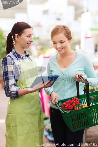 Image of happy women with tablet pc in greenhouse