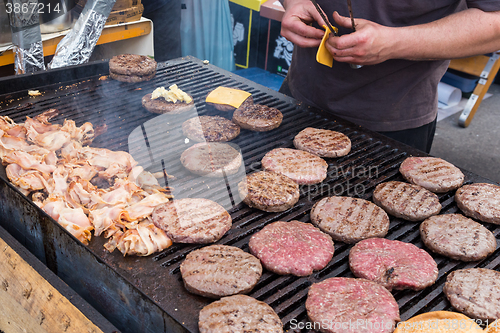 Image of Beef burgers being grilled on food stall grill.