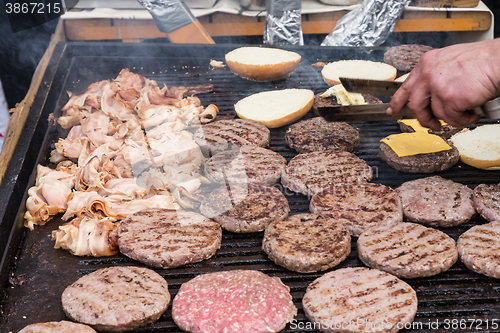 Image of Beef burgers being grilled on food stall grill.