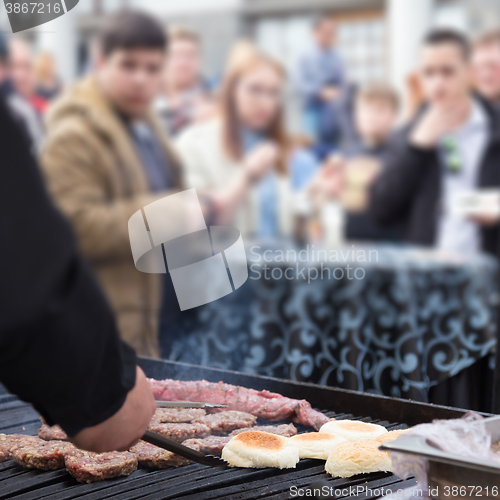 Image of Beef burgers being grilled on food stall grill.