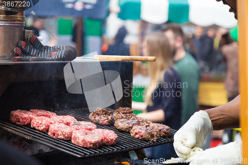 Image of Beef burgers being grilled on food stall grill.