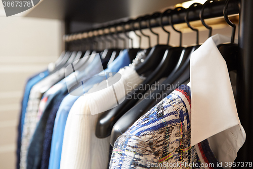 Image of Clothes on hangers in shop.