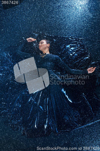 Image of The young beautiful modern dancer dancing under water drops