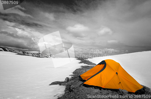 Image of Orange tent in snow mountains. Selective color.