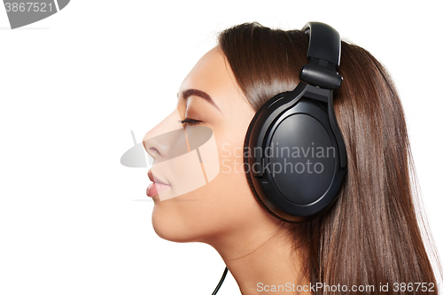 Image of Female listening enjoying music in headphones with closed eyes