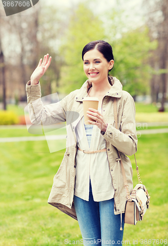 Image of smiling woman drinking coffee in park