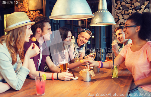 Image of happy friends with drinks talking at bar or pub