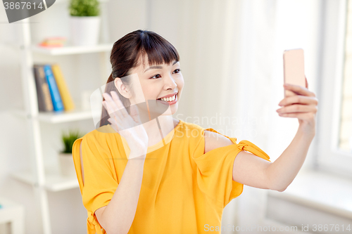 Image of happy asian woman taking selfie with smartphone