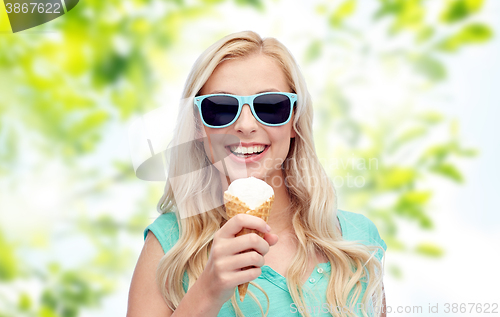 Image of happy young woman in sunglasses eating ice cream