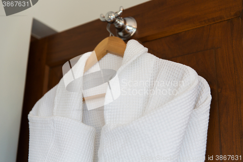 Image of close up of white bathrobes on wooden hanger