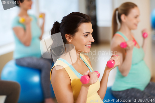 Image of happy pregnant women exercising on fitball in gym