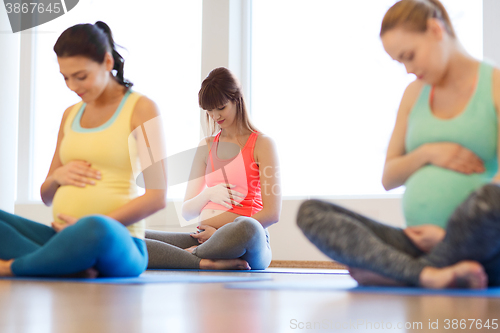 Image of happy pregnant women exercising yoga in gym