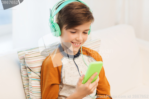 Image of happy boy with smartphone and headphones at home