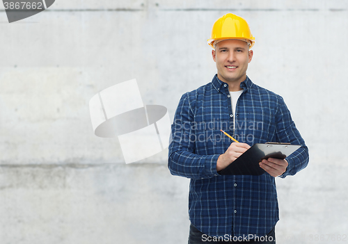 Image of smiling male builder in helmet with clipboard