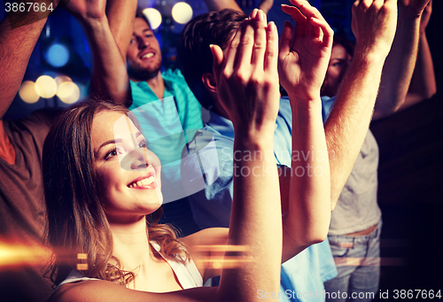 Image of smiling friends at concert in club