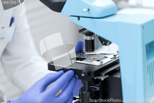 Image of close up of hands with microscope and blood sample