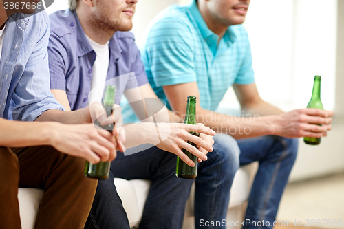 Image of happy male friends with beer watching tv at home