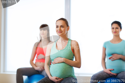 Image of happy pregnant women exercising on fitball in gym