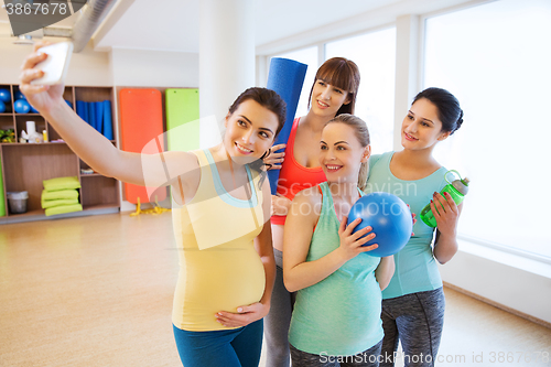 Image of pregnant women taking selfie by smartphone in gym