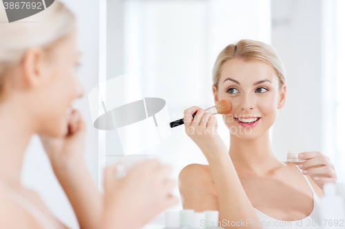 Image of woman with makeup brush and powder at bathroom