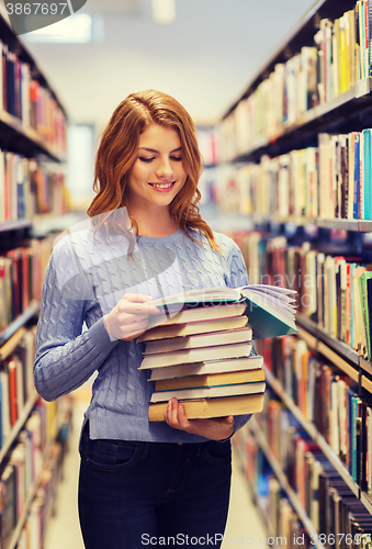 Image of happy student girl or woman with books in library