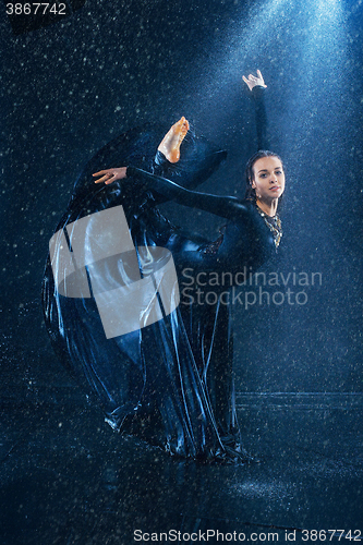 Image of The young beautiful modern dancer dancing under water drops