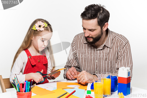 Image of The daughter and father carving out paper applications 