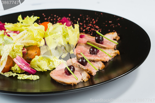 Image of grilled meat with lettuce. on black plate