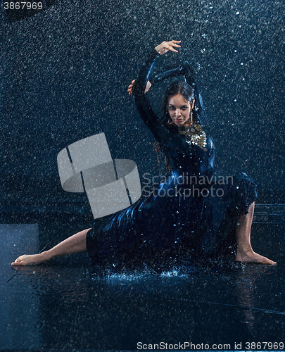 Image of The young beautiful modern dancer dancing under water drops