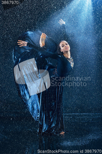 Image of The young beautiful modern dancer dancing under water drops