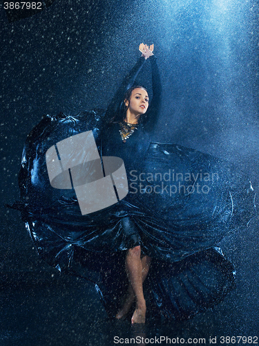 Image of The young beautiful modern dancer dancing under water drops