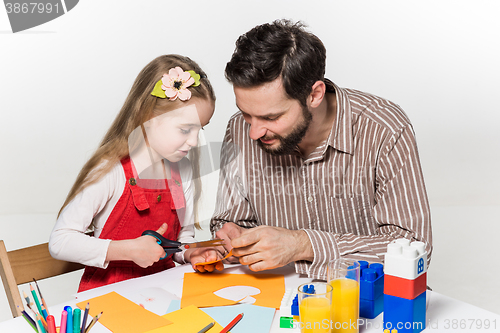 Image of The daughter and father carving out paper applications 