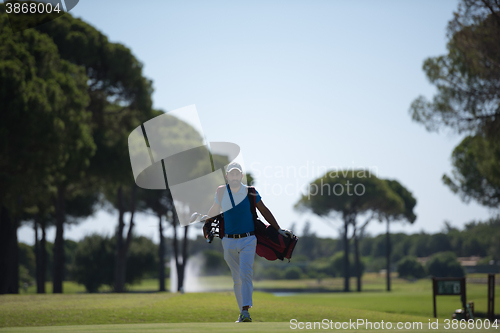 Image of golf player walking and carrying bag