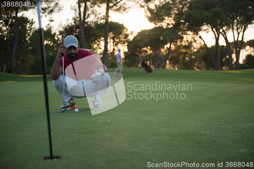 Image of golf player aiming perfect  shot on beautiful sunset