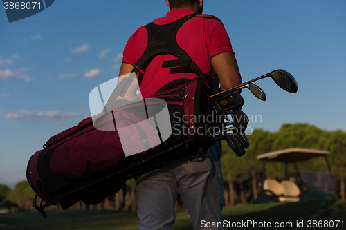 Image of close up of golfers back while   walking and carrying golf  bag