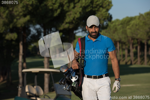 Image of golfer  walking and carrying golf  bag