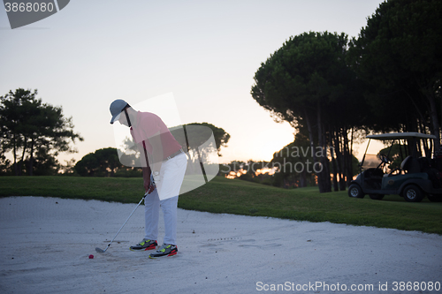 Image of golfer hitting a sand bunker shot on sunset