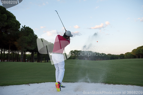 Image of golfer hitting a sand bunker shot on sunset