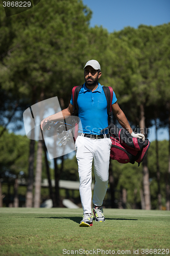 Image of golf player walking and carrying bag