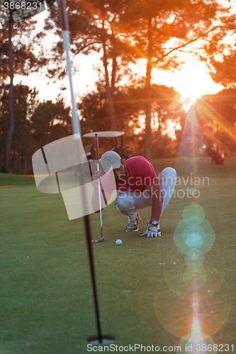 Image of golf player aiming perfect  shot on beautiful sunset