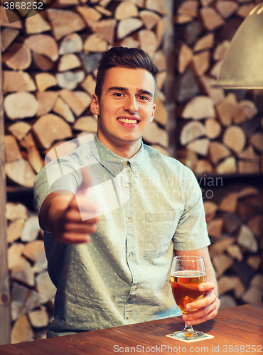 Image of happy man with beer showing thumbs up at bar