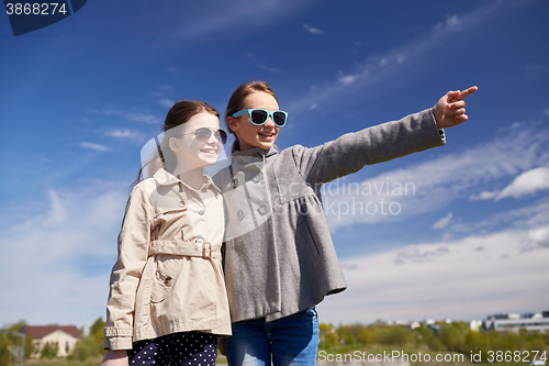 Image of happy little girls hugging and pointing finger