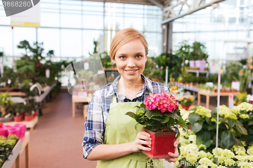 Image of happy woman holding flowers in greenhouse