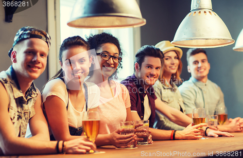 Image of happy friends drinking beer and cocktails at bar