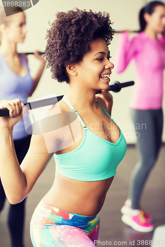 Image of group of people exercising with bars in gym