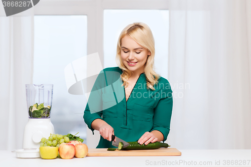 Image of smiling woman with blender cooking food at home